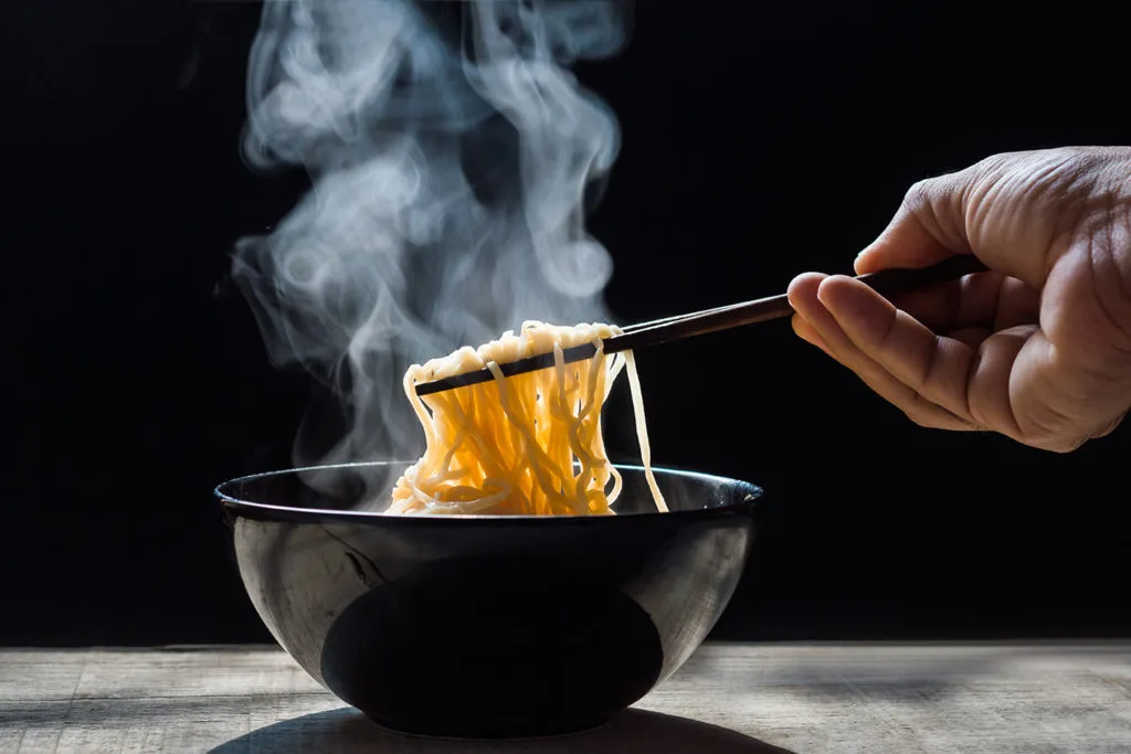 Chopsticks picking up ramen from a bowl